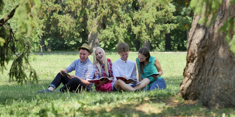 Medium happy people sitting under the tree studying reading and laughing students girls and boys are preparing to exams at the nature university college campus se ig0vq thumbnail full01